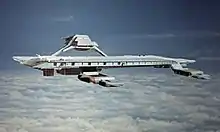 An airborne structure resembling a seagoing aircraft carrier, hovering at high altitude above clouds