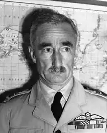 Head-and-shoulders portrait of moustachioed man in light-coloured military uniform with ribbons and pilot's wings on chest