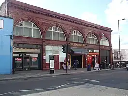 A red-bricked building with "CALEDONIAN RD." in gold letters and a blue sign reading "CALEDONIAN ROAD STATION" in white letters below