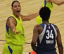 Young woman smiling and extending arm towards camera after struggle with Sylvia Fowles