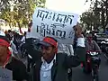 An opposition protester marches, holding up a sign that says "Re-election".