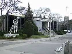 External view of the museum clad in steel and glass with a statue depicting as in-game football catch and tackle