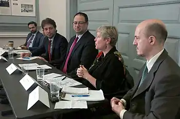 Elise Bean talks as Guillaume Long, former Ecuadorian politician who served as the Minister of Foreign Affairs of Ecuador and Human Mobility, and others look on.