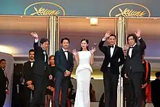 A cast, including Yeun smiling and waving