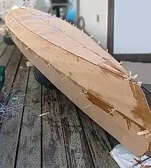 A stitched canoe hull under construction.