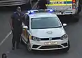 A Cape Town Metropolitan Police officer with a Metro Police vehicle.