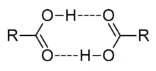 This image illustrates how two carboxylic acids, C O O H, can associate through mutual hydrogen bonds. The hydroxyl portion O H of each molecule forms a hydrogen bond to the carbonyl portion C O of the other.