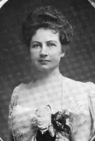 Formal portrait of a white woman in 1901, wearing a beaded gown, with flowers attached to the bodice.