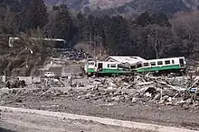 The wreckage of KiHa 48 502 and KiHa 48 1512 following the tsunami, having been swept off the tracks at Onagawa and washed uphill by the wave