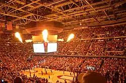 Indoor arena with people lighted by fire.