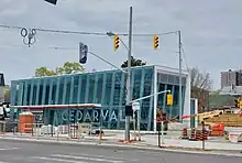 Photo of a modern, glass-panelled light rail station entrance under construction which appears largely complete