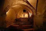 A stone room with a vaulted ceiling an an altar.