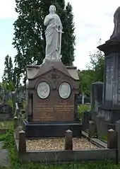 An elaborate funerary monument of red granite, with two white marble tondi of Blondin and his wife, surmounted by a marble statue of a female figure clad in robes holding an anchor