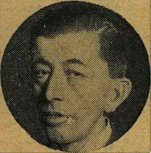 A headshot picture of a dark-haired man, looking towards the camera