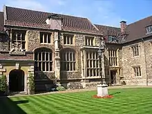 A courtyard of a set of stone buildings with large windows.