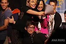 Five young people smiling and embracing while holding scripts.