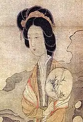 A woman holding a flat oval fan with a Chinese painting from the painting "Appreciating Plums" by Chen Hongshou (1598–1652).