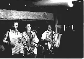 Chenier Brothers performing at Jay's Lounge and Cockpit, Cankton, Louisiana, Mardi Gras, 1975Clifton Chenier on accordion, brother Cleveland on washboard and John Hart on tenor saxophone.