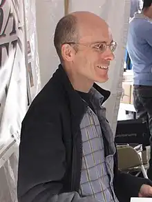 Photo of a bald, middle-aged man wearing glasses