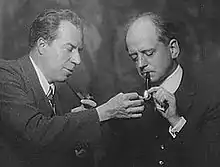 man lighting another man's pipe with a match