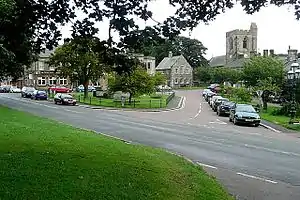 Looking to the junction of Front Street (B6341), in the foreground running left ro right, and Church Street, this street leads from Town Foot to All Saints church.