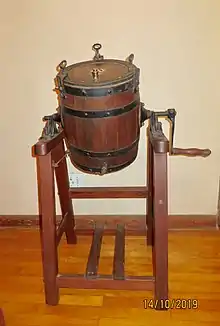 Barrel shaped oak container, rotating on pine framework or stand.  Used in a farm environment to manually agitate cream to produce butter and buttermilk, the byproduct of butter production.