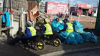 Street Cleaners in Joe Slovo Park, Dilapidated soccer field visible in the background