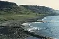 The coast south of Duntulm (1986) where barren high land is broken at lower level by farmable areas. The beach is bouldered. Housing is limited.