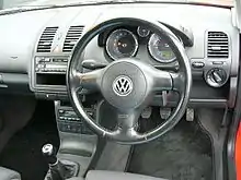 Dashboard of a car with a manual gearbox, digital and analogue gauges, front airbags, and some sort of head unit.