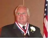 man in business suit wearing medal around neck