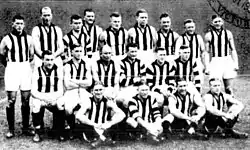 A group of men wearing sleeveless guernseys with black-and-white vertical stripes.