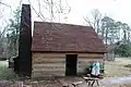 Reconstruction of a log cabin with a clapboard roof.