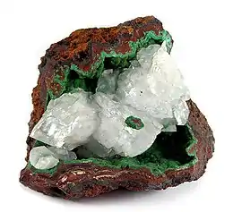 A vug in a limonite matrix is the host for a layer of green botryoids of conichalcite and colorless, translucent rhombs of calcite