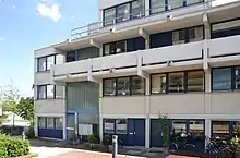 Four-storey building clad in white and grey siding, and a memorial plaque for the hostage incident