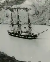 Photograph of a ship being towed through a canal