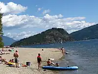 A crowded sand beach along a lake