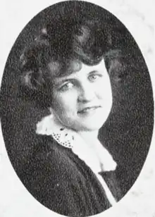 A smiling young white woman with short bouffant hair, wearing a lace collar