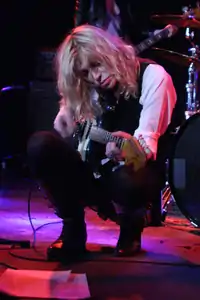 Courtney Love, playing a Fender Mustang guitar in concert.