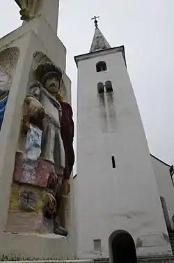 Catholic church of Csatár with a stone cross in the foreground from 1817.