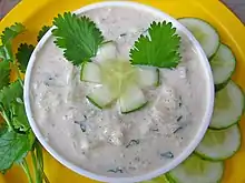 Cucumber raita served with the garnishing of fresh coriander leaves.