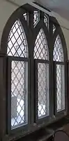 A triptychal window overlaid with diagonal grid paneling and stone tracery