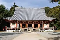 Wooden building with hip-and-gable roof, white walls, vermillionred beams and an open veranda.