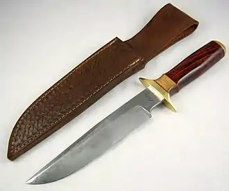 Large knife with polished wooden handle, lying next to a leather sheath