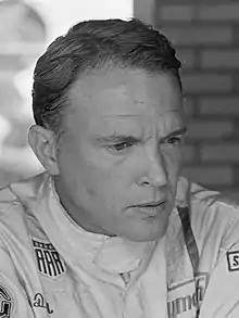 Dan Gurney in a black and white photograph wearing racing overalls