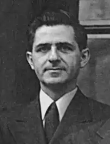 Black and White head and shoulder shot of 30's white male with thick black hair, and a three piece suit from the 1940s