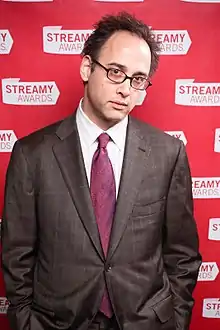 David Wain standing in front of the Streamy Awards red carpet backdrop and facing the camera