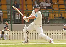 A man wearing yellow Australian jersey playing a shot.