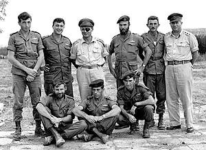 With members of 890th Paratroop Battalion after Operation Egged (November 1955). Standing l to r:  Lt. Meir Har-Zion, Maj. Arik Sharon, Lt. Gen Moshe Dayan, Capt. Dani Matt, Lt. Moshe Efron, Maj. Gen Asaf Simchoni; On ground, l to r:  Capt. Aharon Davidi, Lt. Ya'akov Ya'akov, Capt. Raful Eitan.