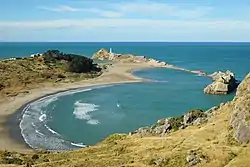 Deliverance Cove towards Castlepoint and lighthouse, residential houses from the Castlepoint village visible on the left