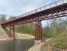 A red metal bridge over a ravine